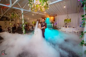 Reception hall filled with dramatic ground fog and ambient lighting for a romantic atmosphere.