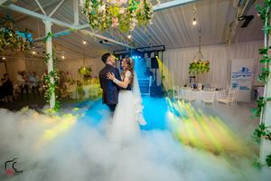 Indoor wedding venue with fog effects and multicolored lighting creating a magical atmosphere.