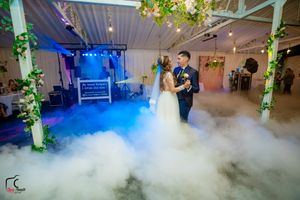 Ethereal fog fills a decorated reception space with dramatic colored lighting effects.