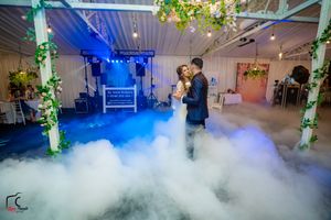 Atmospheric fog blankets a wedding venue dance floor with dramatic colored lighting effects.