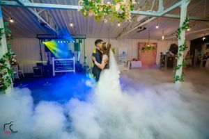 Dense white fog creates a cloud-like effect across an indoor venue with decorative lighting.
