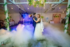 Low-lying fog swirls across an elegant reception venue floor illuminated by blue and green lights.