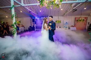 Wedding dance floor filled with dramatic fog effects and colorful mood lighting creating a dreamy atmosphere.