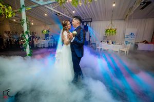 Wedding dance captured with dramatic side lighting and fog effects in a decorated venue.