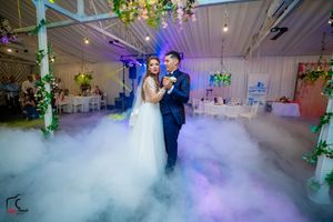Elegant dance moment in a reception hall with purple lighting and dramatic fog effects.