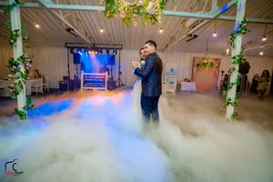 A dance performance in an elegantly lit venue with fog effects and floral-decorated pillars.