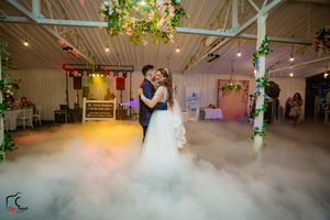 Romantic dance moment captured in a venue with decorative columns and atmospheric fog effects.