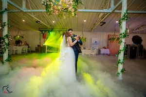 Wedding couple dances amid dramatic yellow and green lighting effects with low-lying fog.