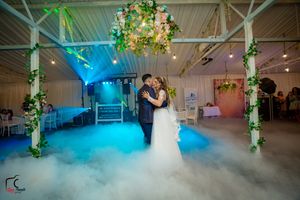Dancing couple surrounded by ethereal fog and blue lighting in an elegant reception venue.