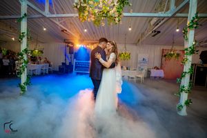 Wedding celebration featuring dramatic fog effects and blue lighting in decorated indoor venue.