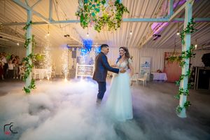 Romantic dance moment captured in fog-filled reception space with elegant lighting and decor.