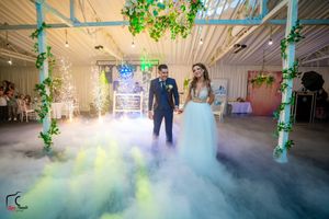 Elegant ballroom filled with misty fog effects and green-lit columns during wedding celebration.