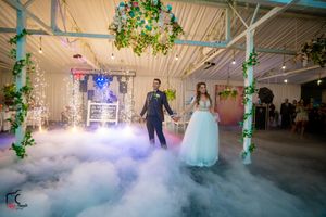 Wedding venue decorated with green vines and atmospheric fog effects during couple's dance.