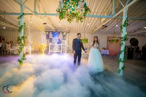 First dance at wedding reception with dramatic low-lying fog and turquoise-lit columns creating ethereal atmosphere.