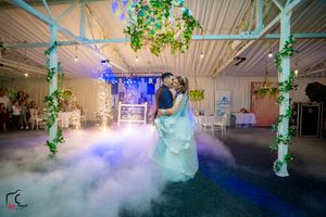 Elegant wedding reception venue with atmospheric fog and multicolored lighting effects.
