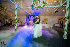 Wedding dance floor filled with blue fog effects and decorative lighting creating magical atmosphere.