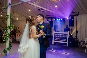 Purple and blue lights illuminate a romantic wedding dance scene with fog effects.