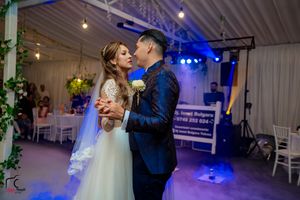 Couple sharing an intimate dance in a decorated indoor venue with dramatic lighting effects.