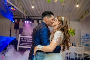 Romantic dance moment captured under blue lighting with fog effects at wedding reception.
