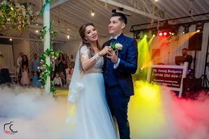 Wedding couple dancing in an indoor venue with atmospheric fog and green accent lighting.