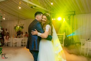 Wedding couple embraces on foggy dance floor with warm yellow lighting creating romantic atmosphere.