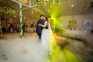 Wedding dance captured with dramatic yellow lighting and fog effects in an elegantly decorated venue.