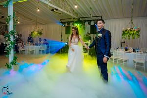 Wedding reception venue features atmospheric fog effects with blue and yellow lighting creating a dreamy ambiance.