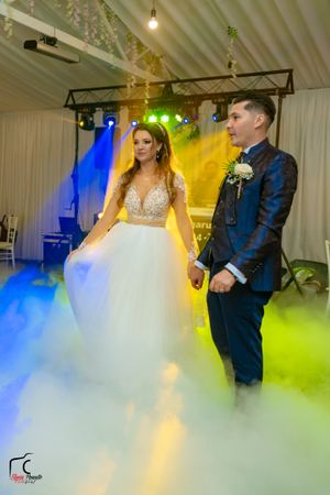 Wedding couple stands in ethereal fog with dramatic blue and yellow lighting effects during their reception.
