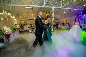 Wedding celebration features dancers moving through atmospheric fog effects under decorative lighting.