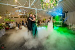 Wedding reception dance floor filled with dramatic fog and green lighting effects in a decorated indoor venue.