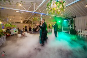 Dancers move gracefully through low-lying fog on a dance floor illuminated by green spotlights.