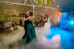 Wedding venue features dramatic lighting and fog effects creating an enchanted dance floor atmosphere.