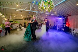 Atmospheric smoke effects and mood lighting create a dreamy ambiance at an indoor wedding venue.