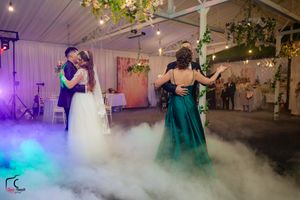 Indoor wedding venue transformed with dramatic fog and colored lighting effects during evening reception.
