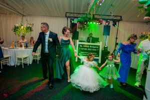 Dancers in formal attire moving across a green-lit dance floor at an elegant indoor celebration.