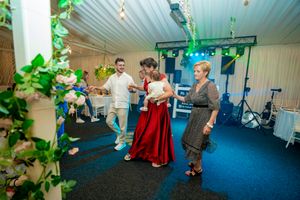 People dancing together in a decorated indoor venue with blue lighting and greenery accents.