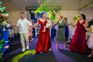 Dancers in formal wear performing synchronized moves at an indoor reception with theatrical lighting.