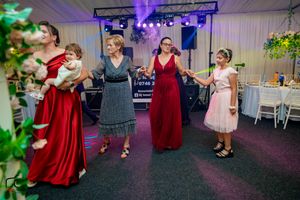 Reception attendees dancing in a line formation under colorful spotlights and stage effects.