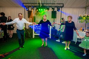 Event guests dancing in formation on a carpeted floor with dramatic green and blue lighting effects.