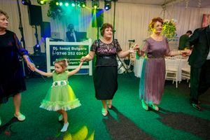 Dancers in formal attire performing group choreography under green and blue stage lighting.