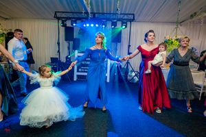 Wedding reception guests dancing together on a dance floor illuminated with blue lighting and stage effects.