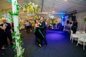 Spacious dance venue decorated with hanging greenery and atmospheric lighting for an evening event.