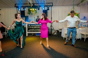 Group dance performance with colorful outfits on blue carpeted floor under stage lighting.
