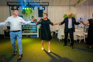 Dance performance on blue carpeted floor with stage lighting and green foliage decorations.