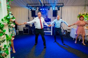 Group dance routine being performed at an indoor venue with blue floor and decorative lighting.