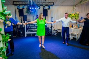 Wide angle view of dancers moving across a blue-carpeted floor under stage lighting.
