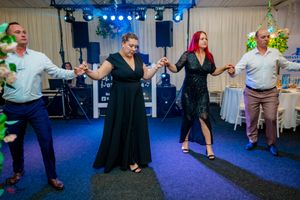 Dancers performing energetic moves on a purple dance floor at an indoor social event.