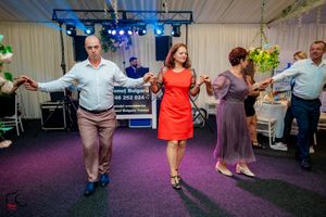 Panoramic shot of dancers moving across a purple-carpeted dance floor at an indoor event.