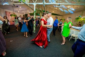 Wide view of a dance floor showing multiple couples dancing at a social gathering.