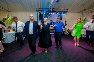 Guests participating in group dance at an indoor reception with purple lighting effects.